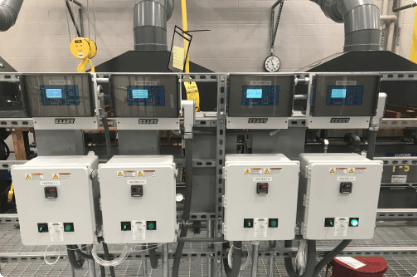 Industrial equipment with four control panels, each displaying digital screens.
